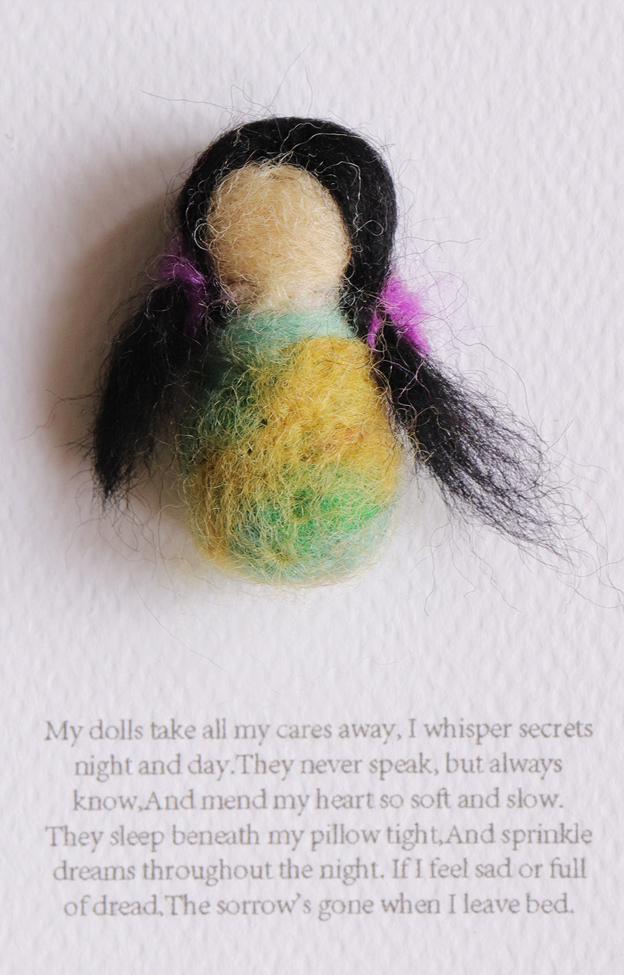 Felted doll with colorful hair on a white background