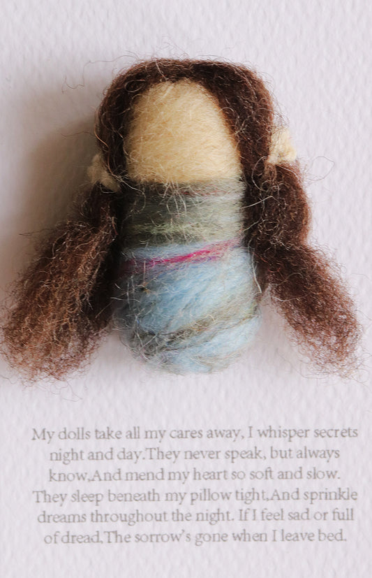 Textile art doll with brown hair and a blue garment on a white background