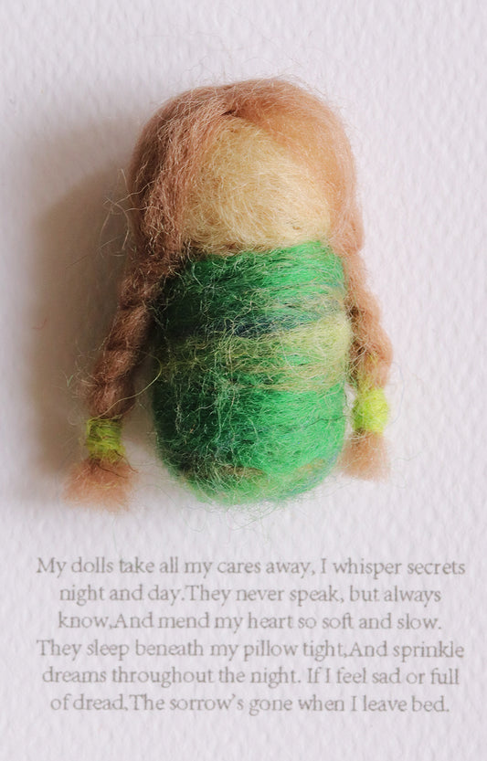 Small felted doll with green body and brown hair on a white background